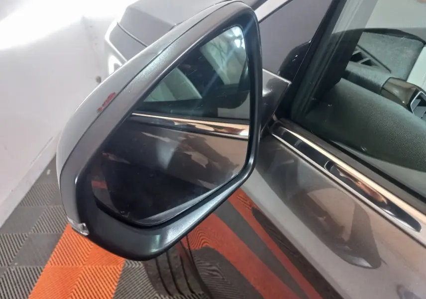 Rétroviseur côté gauche du DS7 Crossback gris foncé, avec reflet de l’habitacle et carrosserie visible en arrière-plan.