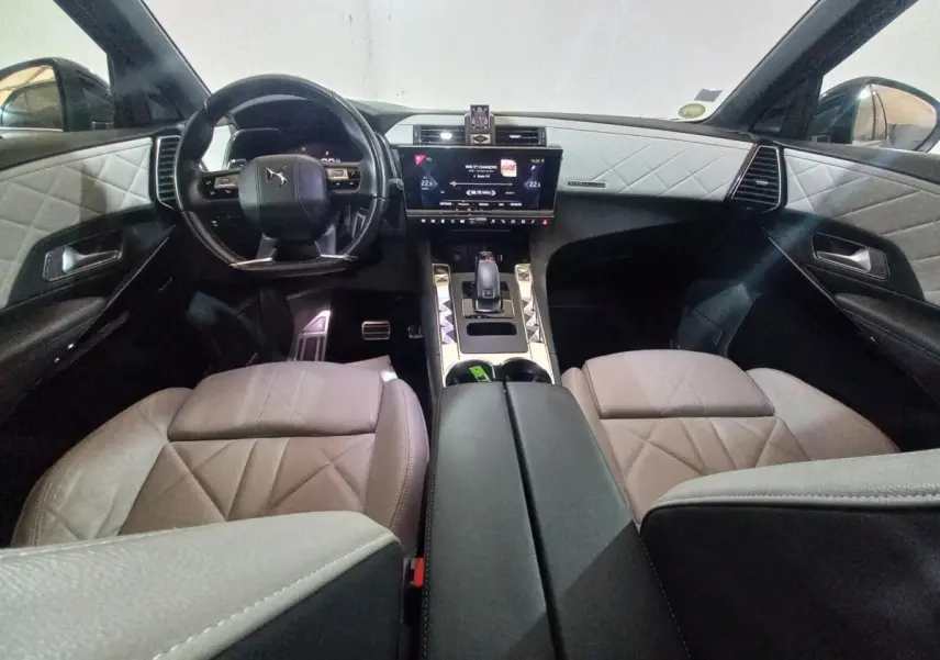 Vue intérieure avant du DS7 Crossback 2021, sièges et panneaux gris clair avec coutures losanges, tableau de bord noir.