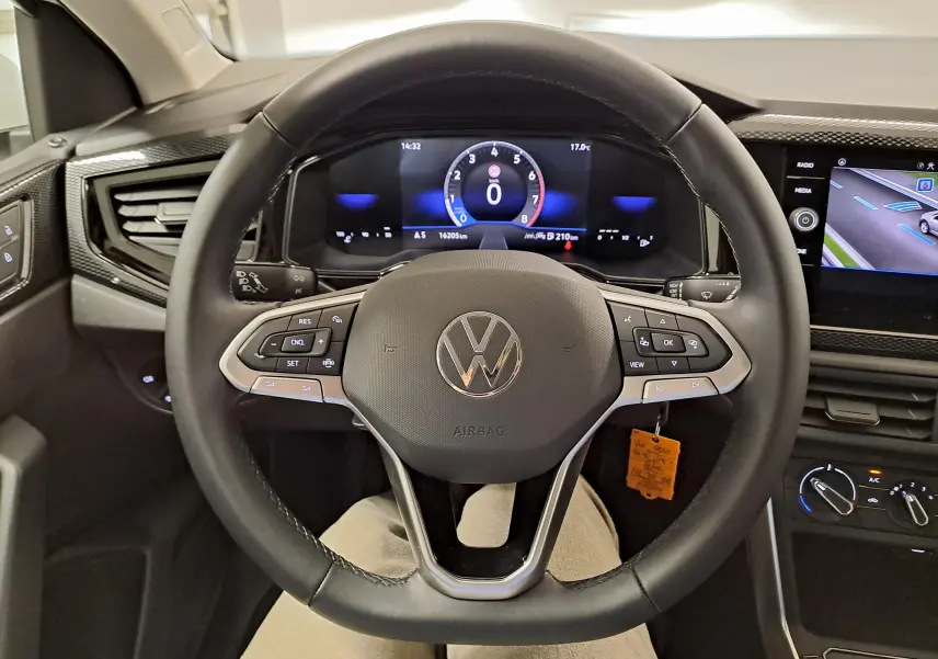 Vue intérieure centrée sur le volant multifonction d'une Volkswagen Polo blanche 2024 avec tableau de bord numérique et écran tactile.
