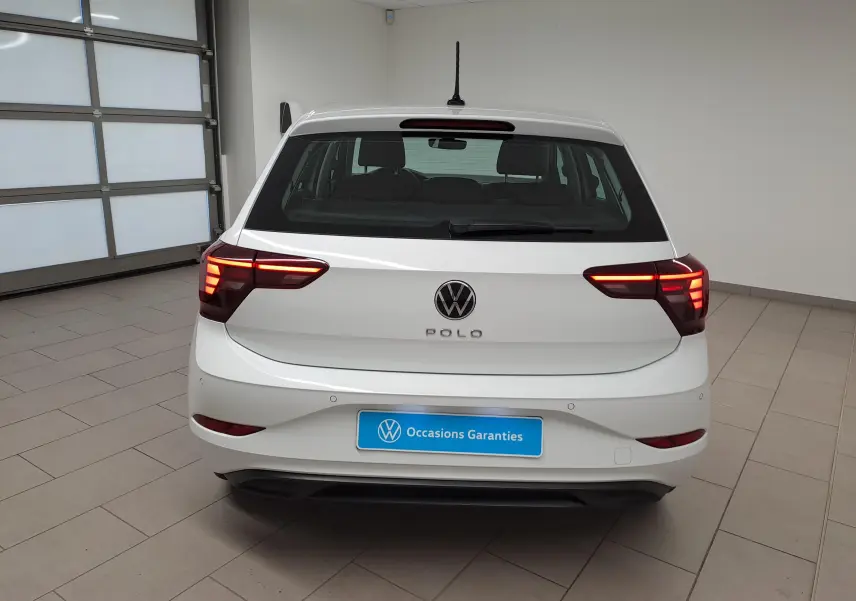 Vue arrière d'une Volkswagen Polo blanche 2024 avec feux arrière allumés dans un showroom lumineux.