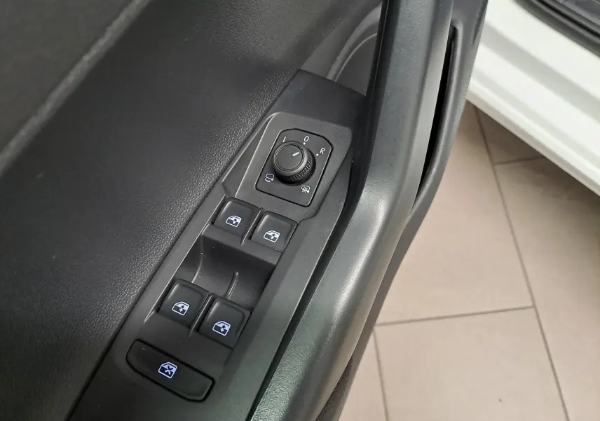 Vue rapprochée des commandes de lève-vitres et réglage des rétroviseurs côté conducteur d'une Volkswagen Polo blanc pur 2024.