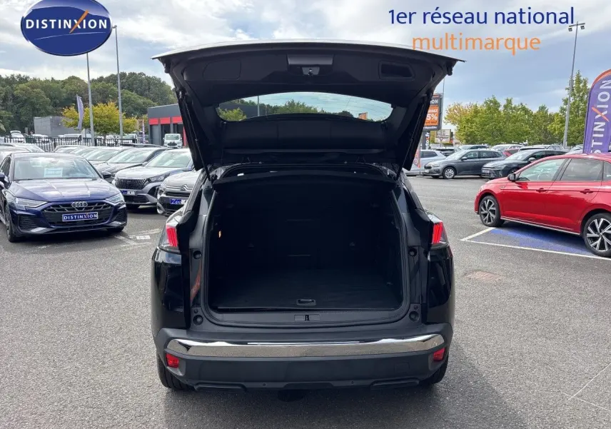Vue arrière d’un Peugeot 3008 noir métal 2024 avec coffre ouvert sur parking multimarque.