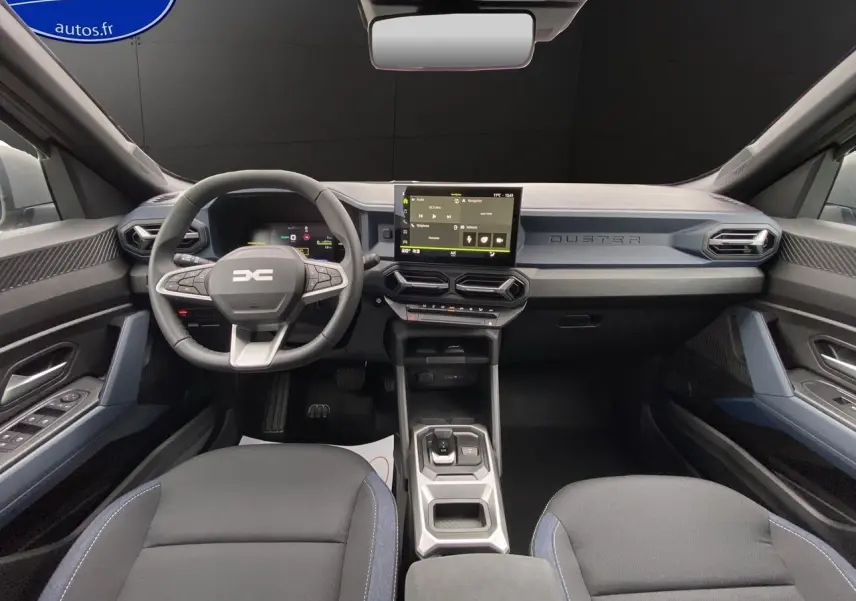 Vue intérieure avant du Dacia Duster 2025, tableau de bord moderne avec écran tactile et volant multifonction noir et bleu.