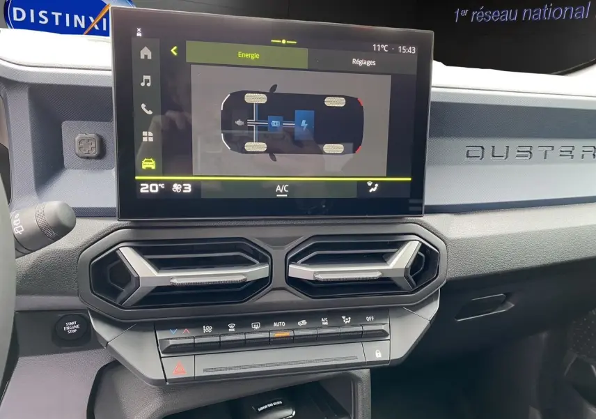 Tableau de bord du Dacia Duster hybride 2025 avec écran tactile affichant l'énergie et aérateurs hexagonaux noirs.
