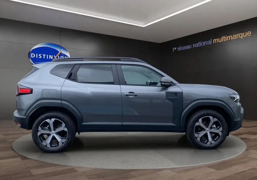 Profil droit du Dacia Duster 2025 gris schiste hybride 140 Journey 4x2 avec jantes alliage et toit noir.