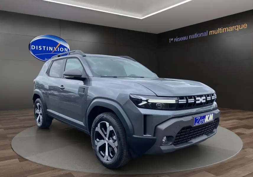 Vue 3/4 avant du Dacia Duster gris schiste hybride 140 Journey 4x2 avec jantes alliage et pack City visible.
