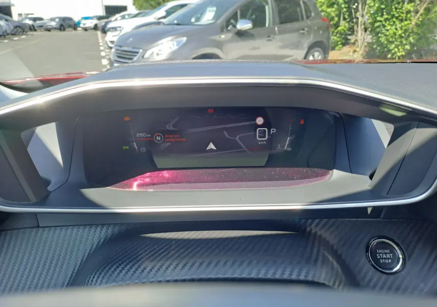 Tableau de bord numérique du Peugeot 2008 rouge 2021, affichant la navigation et le bouton start/stop sur fond carbone.