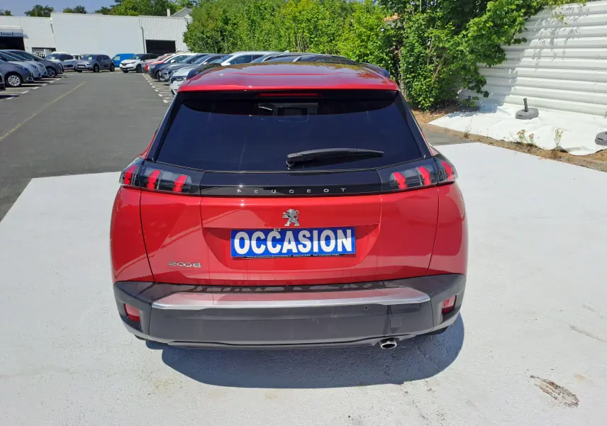 Vue arrière d'un Peugeot 2008 rouge 2021 avec feux arrière à griffes et plaque "OCCASION" visible.