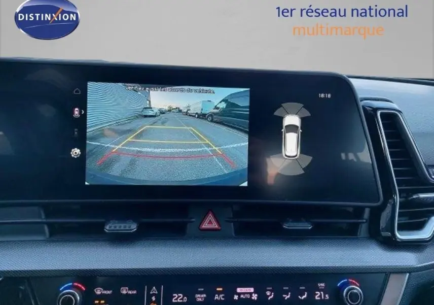 Écran central du Kia Sportage 2024 montrant la caméra de recul et les capteurs d’aide au stationnement.