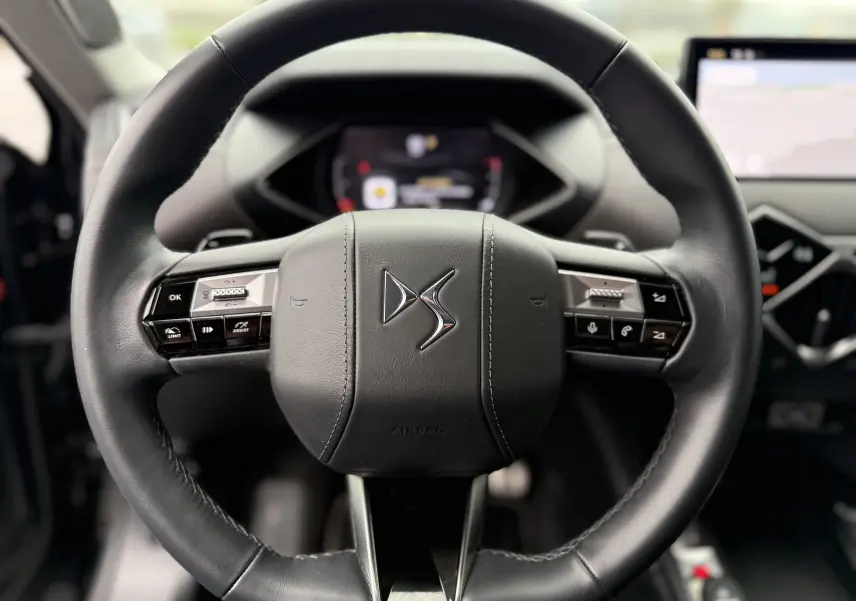 Gros plan sur le volant en cuir noir du DS3 2024, avec commandes intégrées et logo DS au centre.