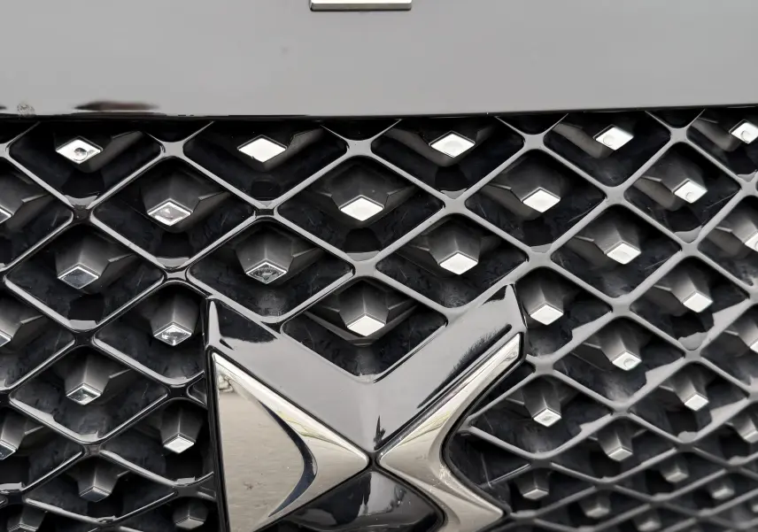 Gros plan sur la calandre noire perla nera du DS3 BlueHDi 130 Étoile avec logo DS chromé et badge Étoile distinctif.