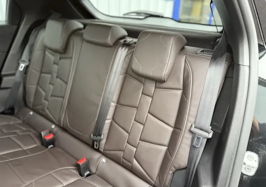 Vue rapprochée des sièges arrière en cuir marron du DS3 2024 noir Perla Nera, avec ceintures de sécurité visibles.