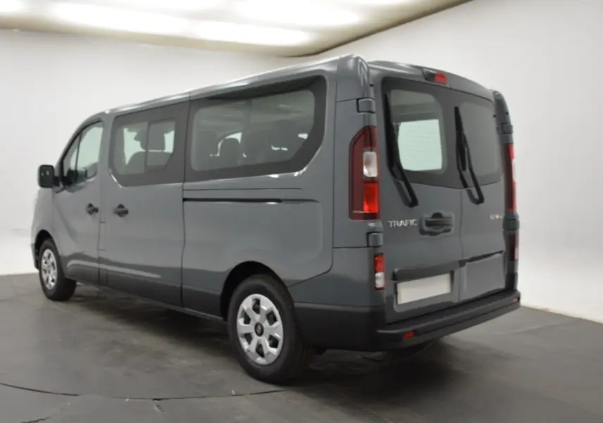 Vue 3/4 arrière droite du Renault Trafic Fourgon gris clair 2025 avec vitres latérales et portes arrière battantes.