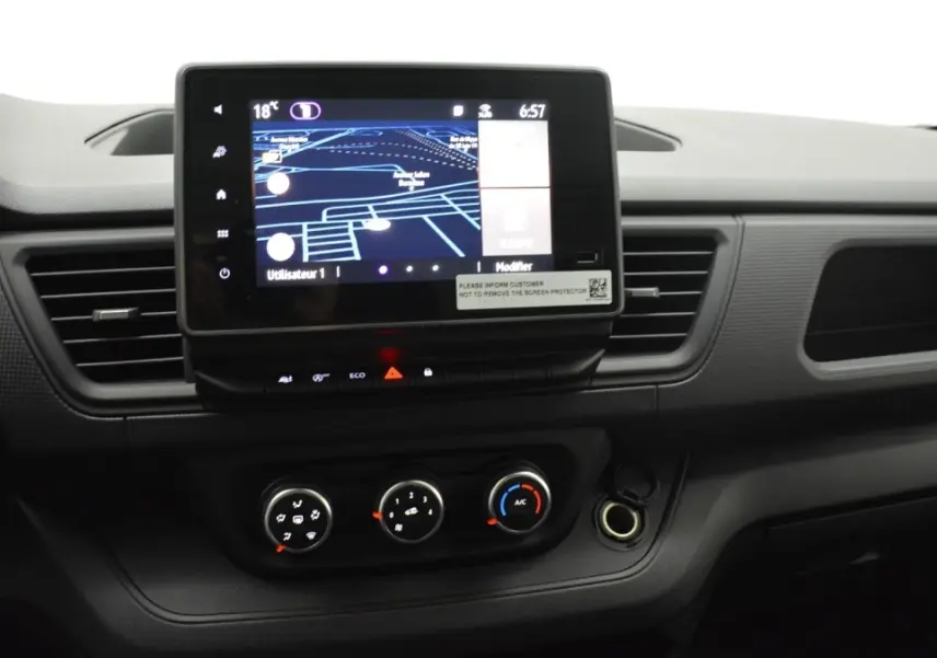 Vue rapprochée du tableau de bord noir du Renault Trafic Fourgon 2025 avec écran tactile central et commandes de climatisation.