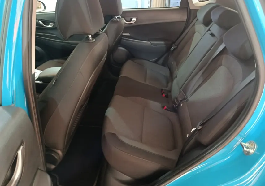Vue intérieure côté droit sur la banquette arrière noire du Hyundai Kona électrique bleu 2022 avec ceinture de sécurité visible.
