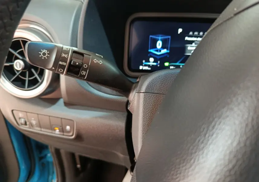 Gros plan sur la manette de commande des phares et clignotants du tableau de bord d’une Hyundai Kona électrique bleue.