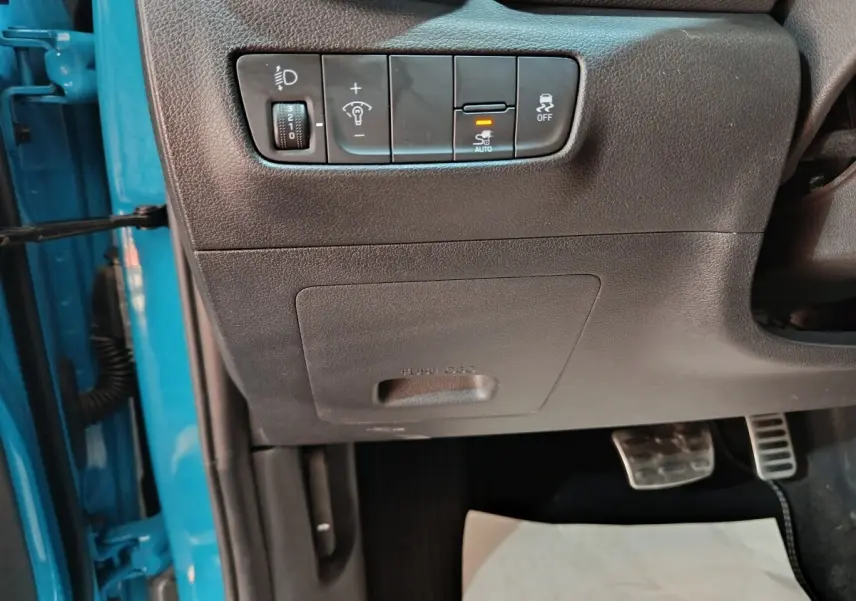 Détail des commandes d’éclairage et de stabilité côté gauche, intérieur noir, portière bleu visible Hyundai Kona électrique 2022.