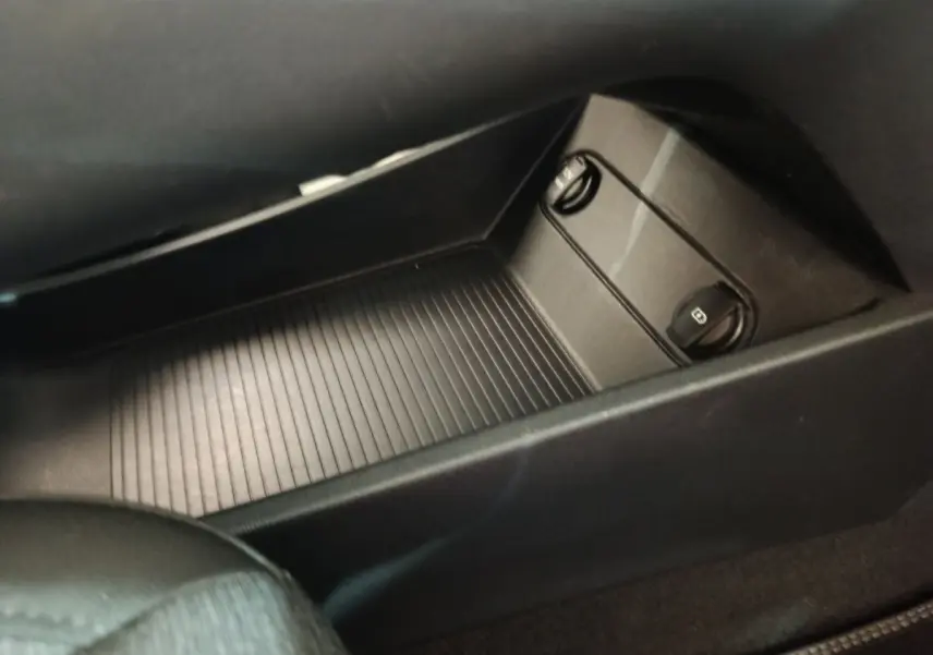 Gros plan sur le rangement central noir avec commandes des vitres dans l’habitacle du Hyundai Kona électrique bleu.