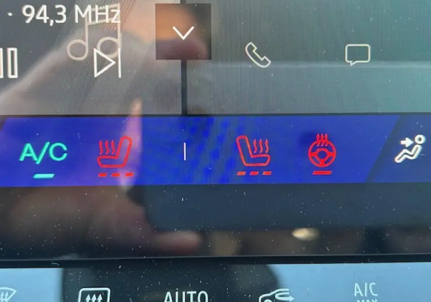 Gros plan sur l'écran tactile intérieur du Renault Symbioz blanc nacré, affichant les commandes de chauffage des sièges et volant.