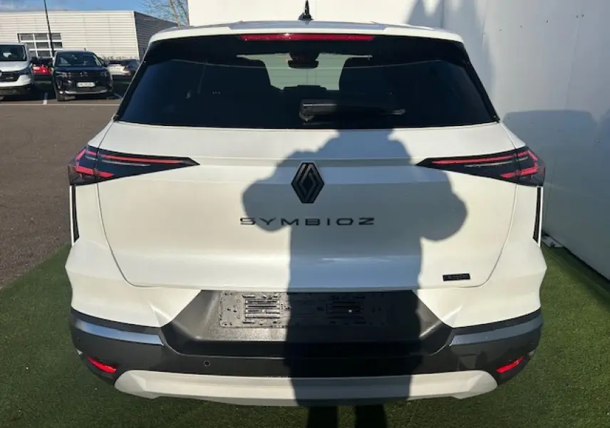 Vue arrière d’un Renault Symbioz blanc nacré avec feux arrière LED fins et logo noir central.