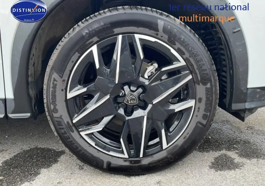 Gros plan sur la roue avant droite du Peugeot 3008 blanc, mettant en valeur la jante alu noire et argentée au design moderne.
