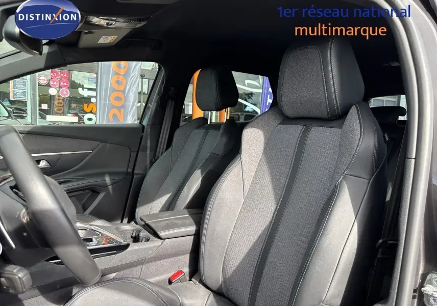 Vue intérieure côté conducteur du Peugeot 3008 Hybrid 180ch Allure 2024, sièges tissu et cuir noir avec surpiqûres grises.