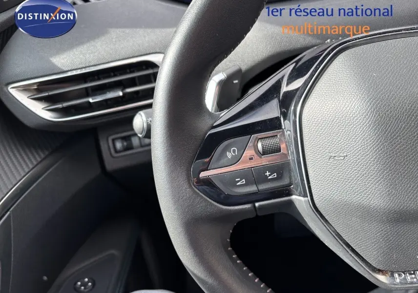Gros plan sur le volant multifonction en cuir noir du Peugeot 3008 Hybrid 2024, avec commandes audio intégrées.