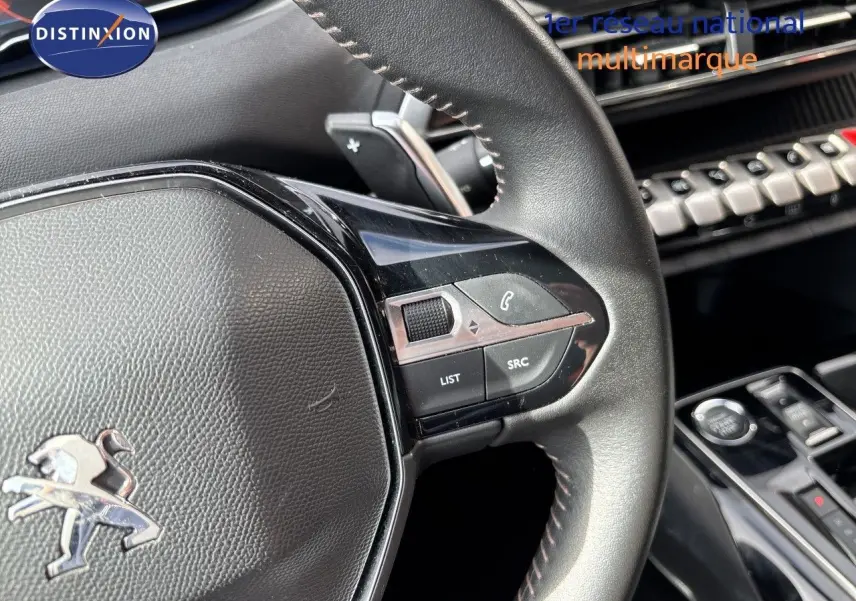 Gros plan sur le volant cuir noir du Peugeot 3008 Hybrid 2024, avec commandes intégrées et tableau de bord partiel visible.