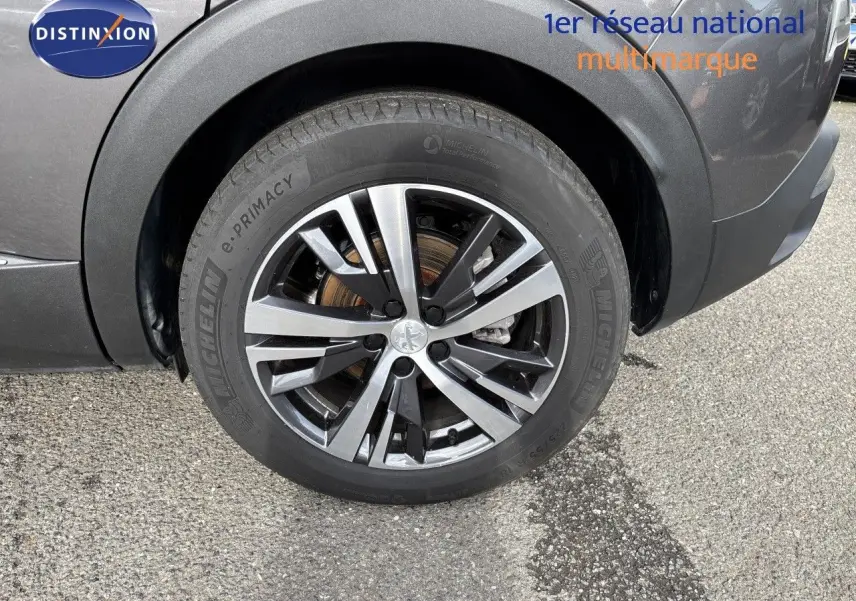 Gros plan sur la roue avant gauche du Peugeot 3008 gris platinium, mettant en valeur la jante alliage bicolore et le pneu Michelin.