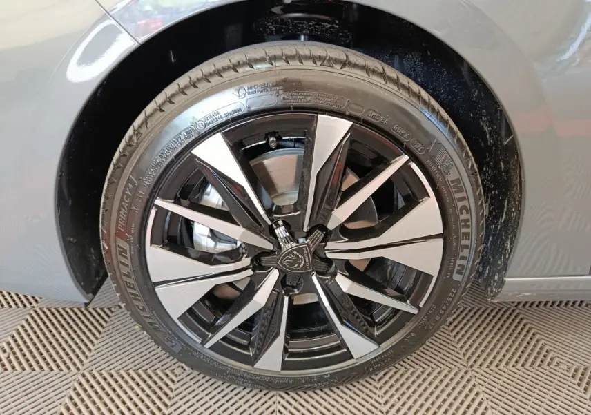 Gros plan sur la roue avant droite de la Peugeot 308 gris foncé, jante alliage noire et argentée au design moderne.