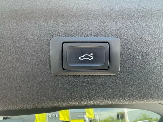 Bouton de déverrouillage électrique du coffre sur le hayon intérieur d'un Audi Q3 blanc diesel de 2015.