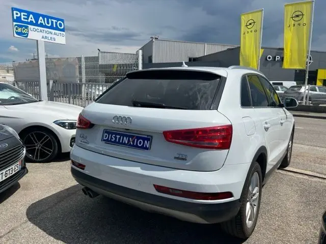 Audi Q3 blanc vue 3/4 arrière droit, avec badges TDI et finition Ambition Luxe, stationné en extérieur.