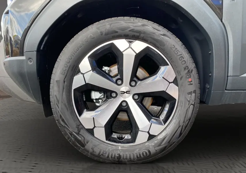 Gros plan sur la roue avant droite du Dacia Duster hybride noir, avec jante alliage bicolore et pneu Continental.
