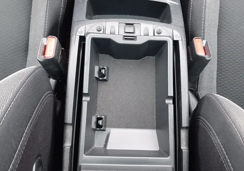 Vue plongeante sur le rangement central noir entre les sièges avant en tissu gris du Nissan Qashqai DCI 115 N-Connecta 2020.