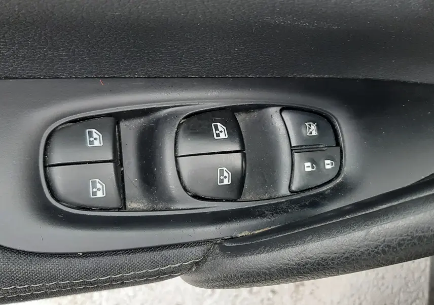 Gros plan sur les commandes de lève-vitres et verrouillage sur la porte côté conducteur d’un Nissan Qashqai noir 2020.