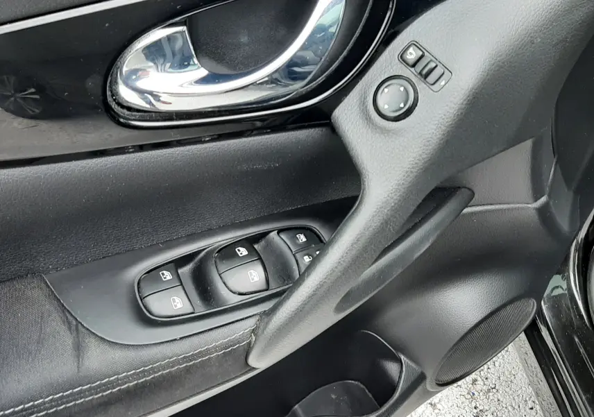 Vue rapprochée de la porte avant gauche noire du Nissan Qashqai 2020, montrant la poignée chromée et les commandes de vitres.
