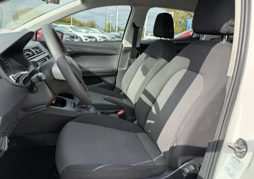 Intérieur avant droit de la SEAT Ibiza 1.6 TDI 2019 blanc Candy, sièges tissu gris et volant multifonction noir.