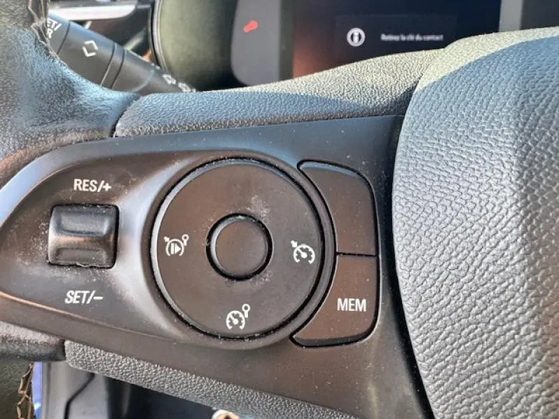 Gros plan sur les commandes du régulateur de vitesse au volant cuir de l'Opel Corsa 1.2 Turbo 2022.
