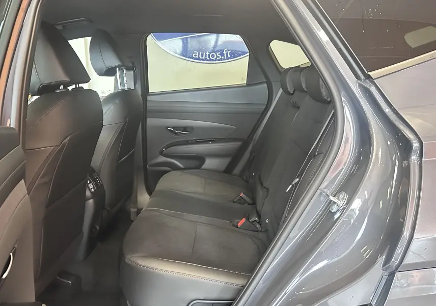 Vue intérieure du tableau de bord du Hyundai Tucson 2025 avec écran tactile affichant les options radio et ambiance lumineuse bleue.