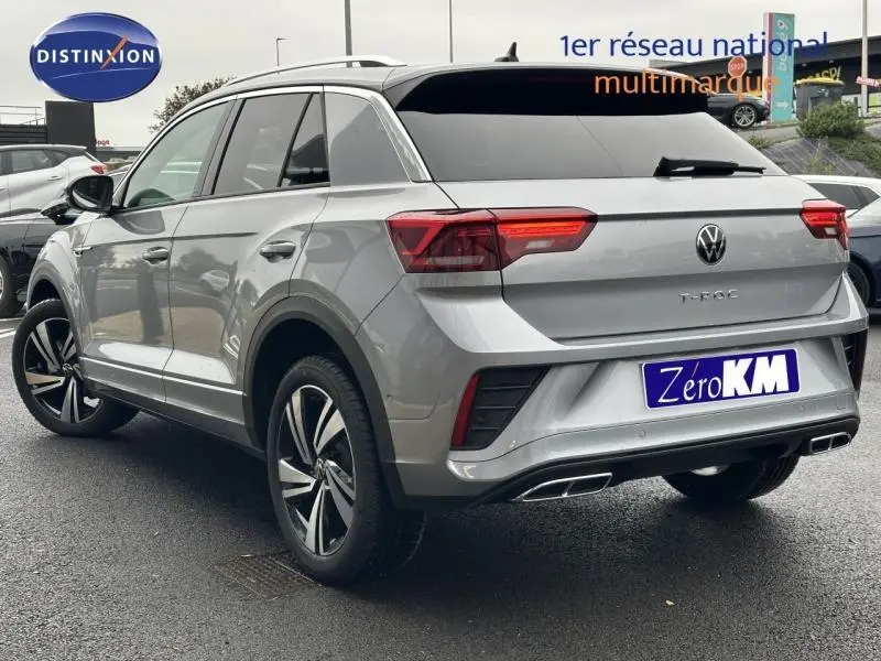 Vue 3/4 arrière droite du Volkswagen T-Roc gris 2025 avec jantes alu et sorties d’échappement chromées double.