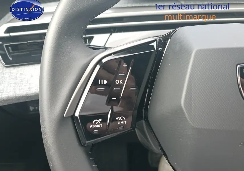 Gros plan sur les commandes multifonctions gauche du volant cuir d’une Peugeot 3008 bleu 2025 hybride.