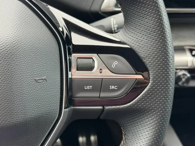 Gros plan sur les commandes à droite du volant perforé du Peugeot 3008 Gris Platinium 2024, boutons LIST et SRC visibles.