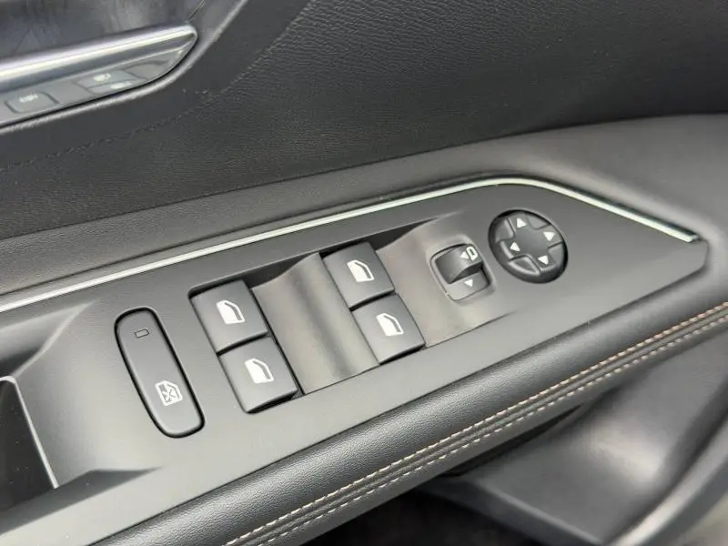 Gros plan sur la commande des vitres électriques côté gauche du Peugeot 3008 2024 Gris Platinium avec surpiqûres marron.