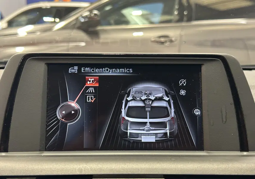 Écran central montrant la dynamique efficace d'une BMW Série 1 gris diesel vue de dessus en schéma numérique.