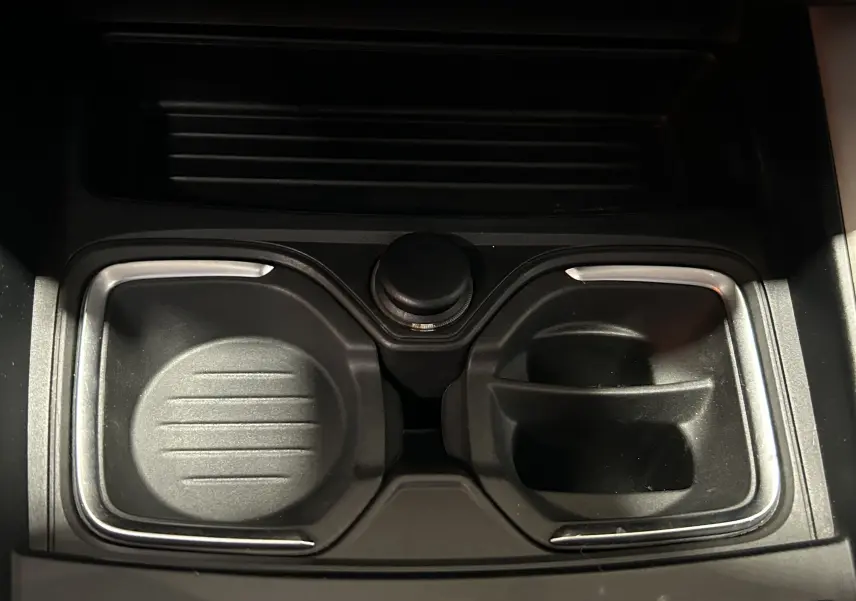 Gros plan sur les porte-gobelets centraux noirs avec contours chromés dans une BMW Série 1 gris diesel de 2014.