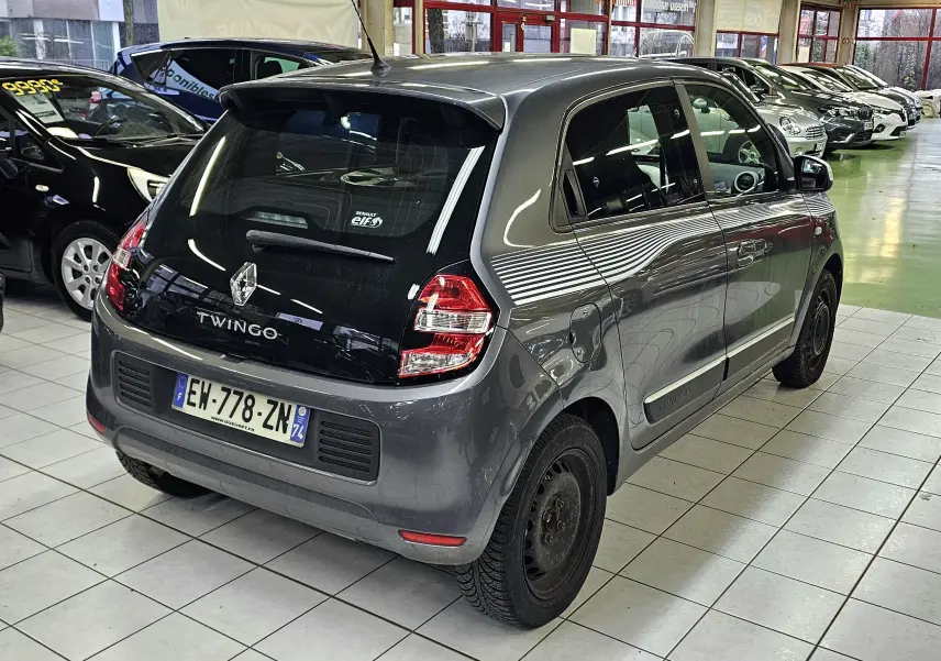 Renault Twingo III gris lunaire vue 3/4 arrière droit en intérieur avec bandes blanches latérales distinctives.