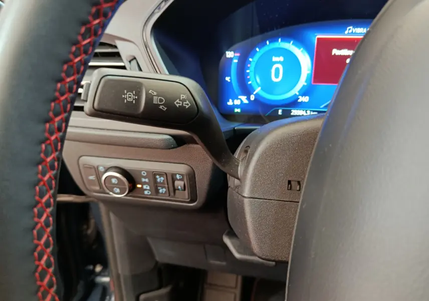 Gros plan sur le commodo gauche et le tableau de bord numérique bleu du Ford Kuga 2024, version St Line.