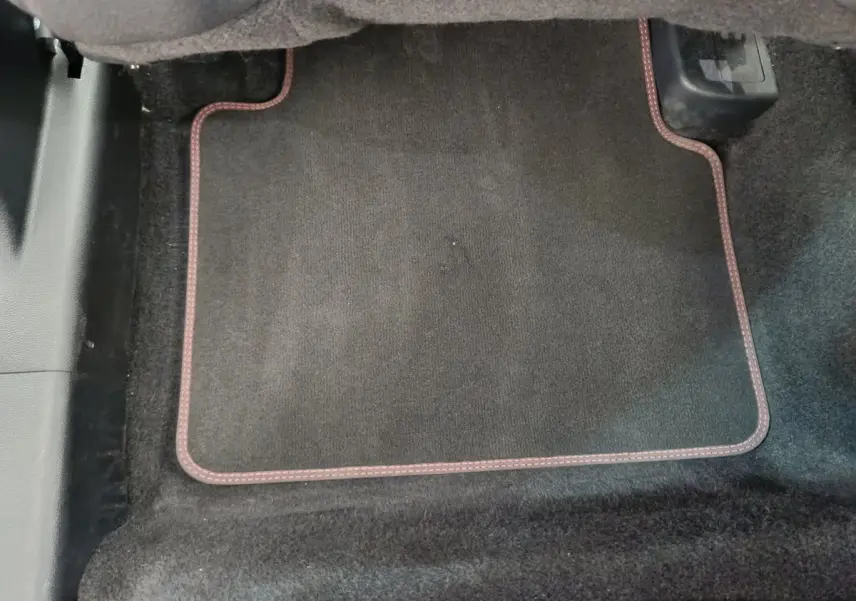 Vue rapprochée du tapis de sol noir avec surpiqûres rouges côté conducteur du Ford Kuga 2024 St Line.