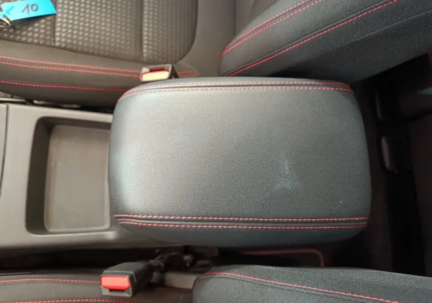 Vue rapprochée de l'accoudoir central noir avec surpiqûres rouges dans l'habitacle du Ford Kuga 2024.