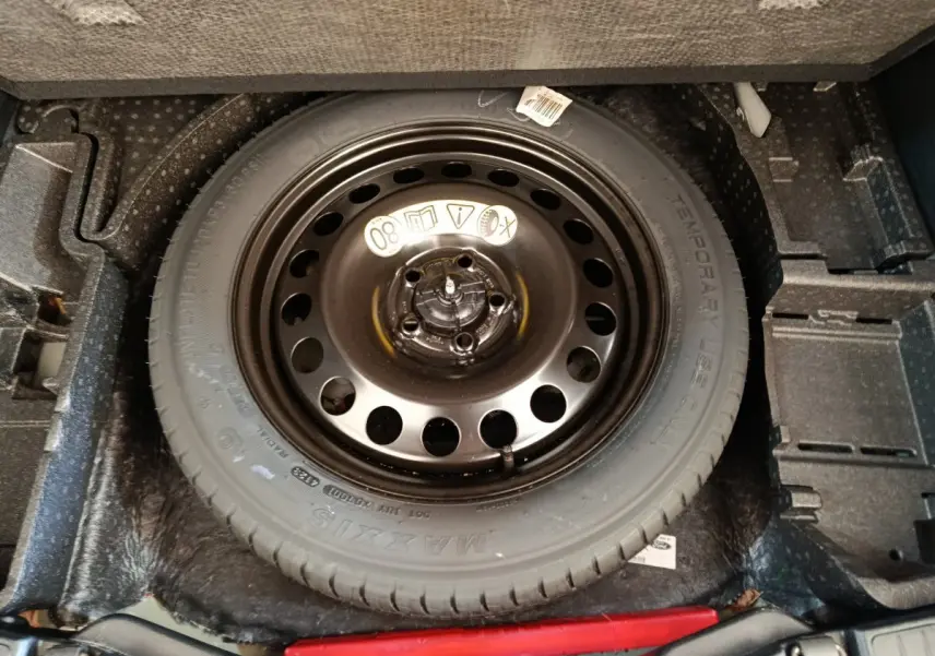 Gros plan sur la roue de secours noire dans le coffre d’un Ford Kuga bleu 2024, version 2.0 EcoBlue St Line.